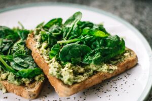 basil leaves and avocado on sliced bread on white ceramic plate