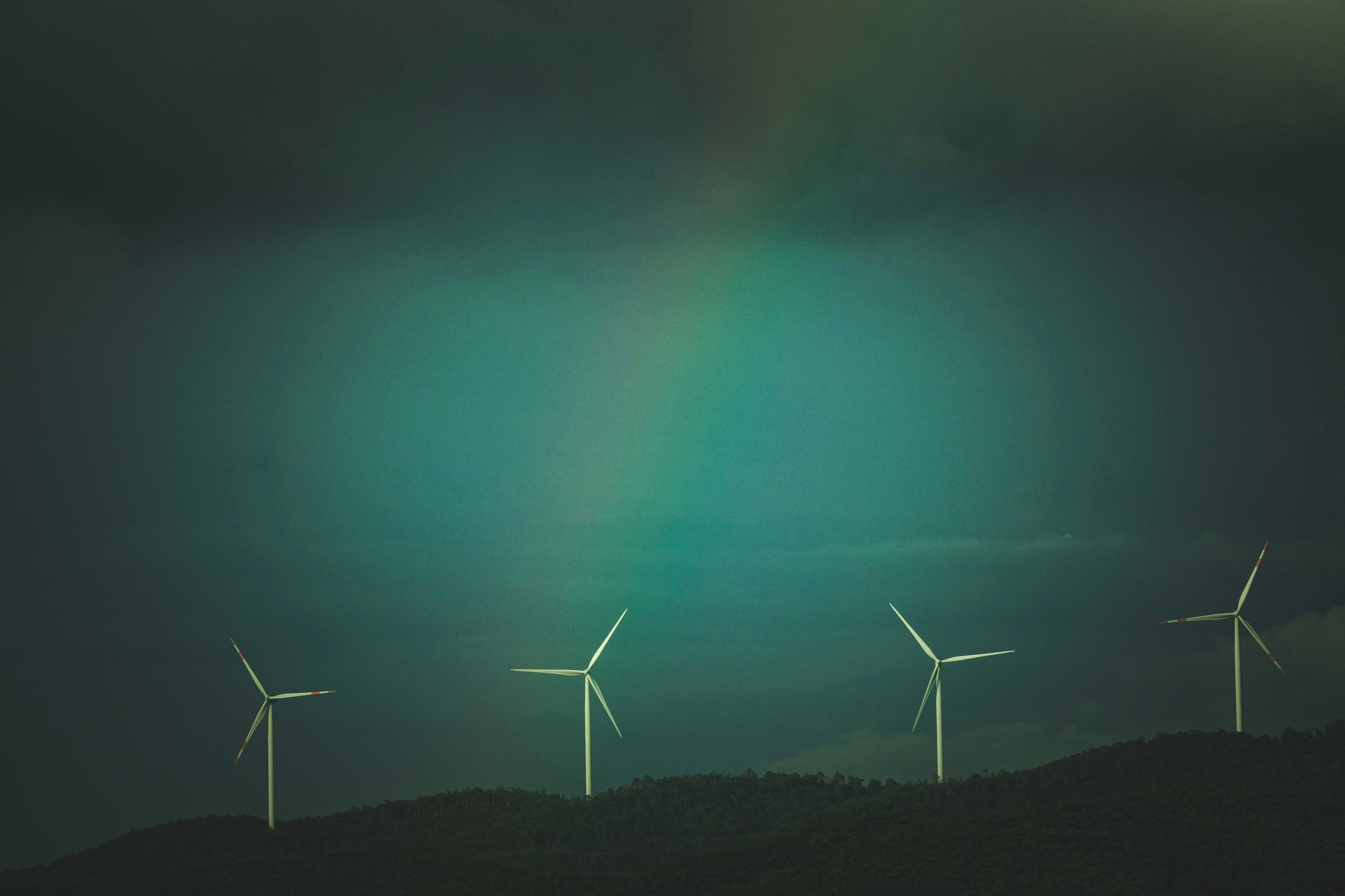 ❓ Frequently Asked Questions (FAQ) About Renewable Energy by Gone Greenish a group of windmills on a hill with a rainbow in the background