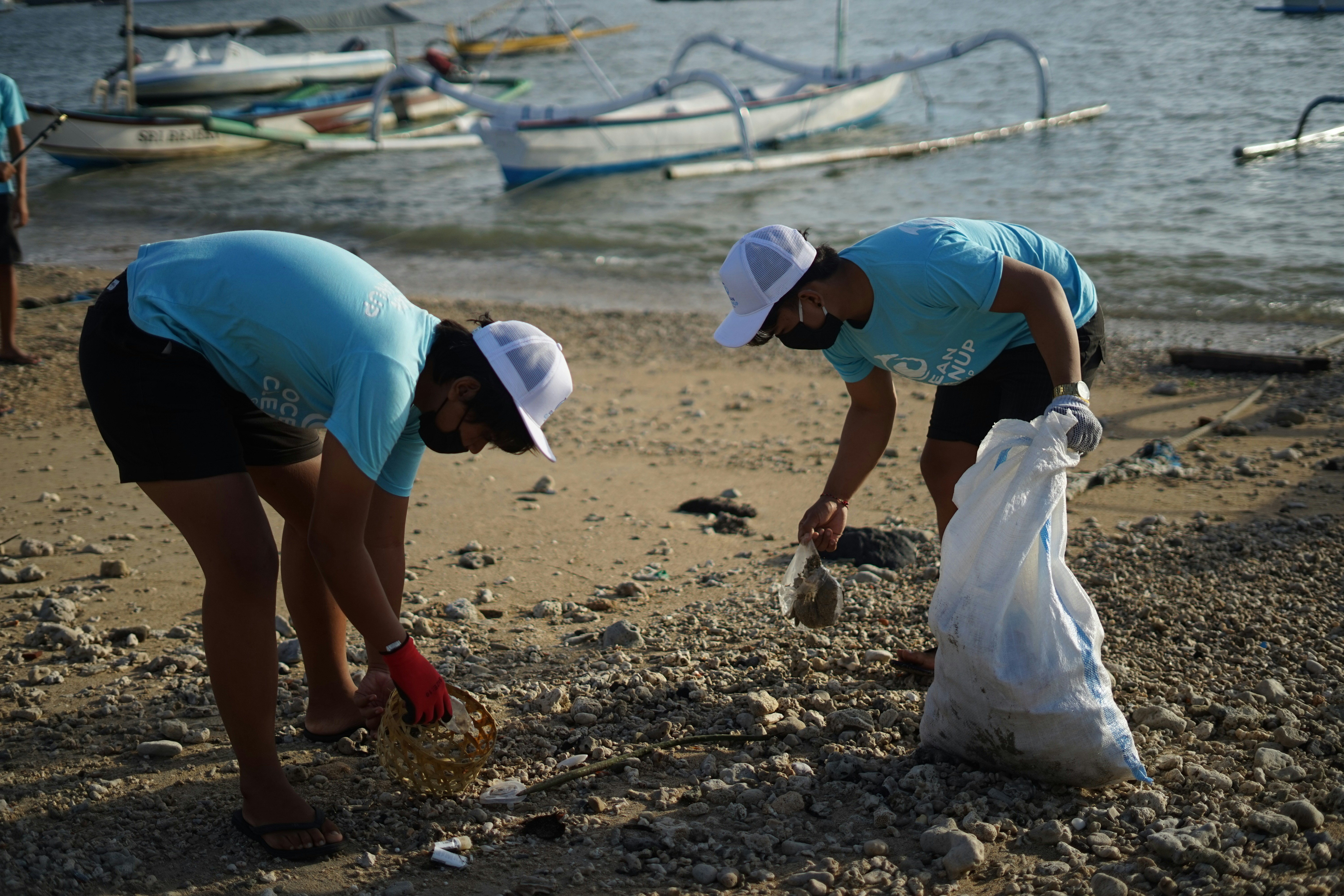 Ocean conservation projects by Gone Greenish woman in blue t-shirt and white helmet holding white plastic bag on beach during daytime