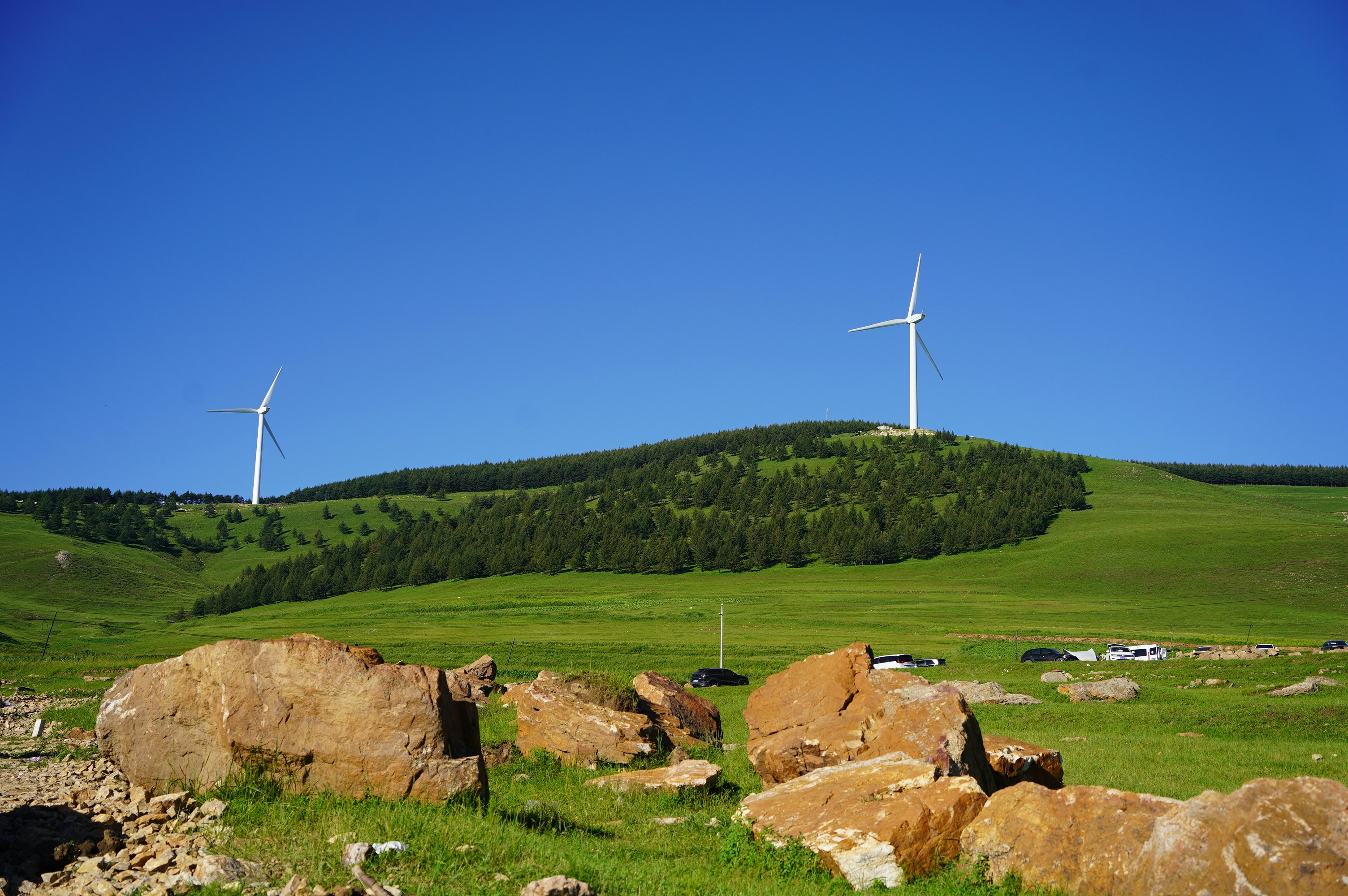 Wind turbines on a grassy hill under a clear sky