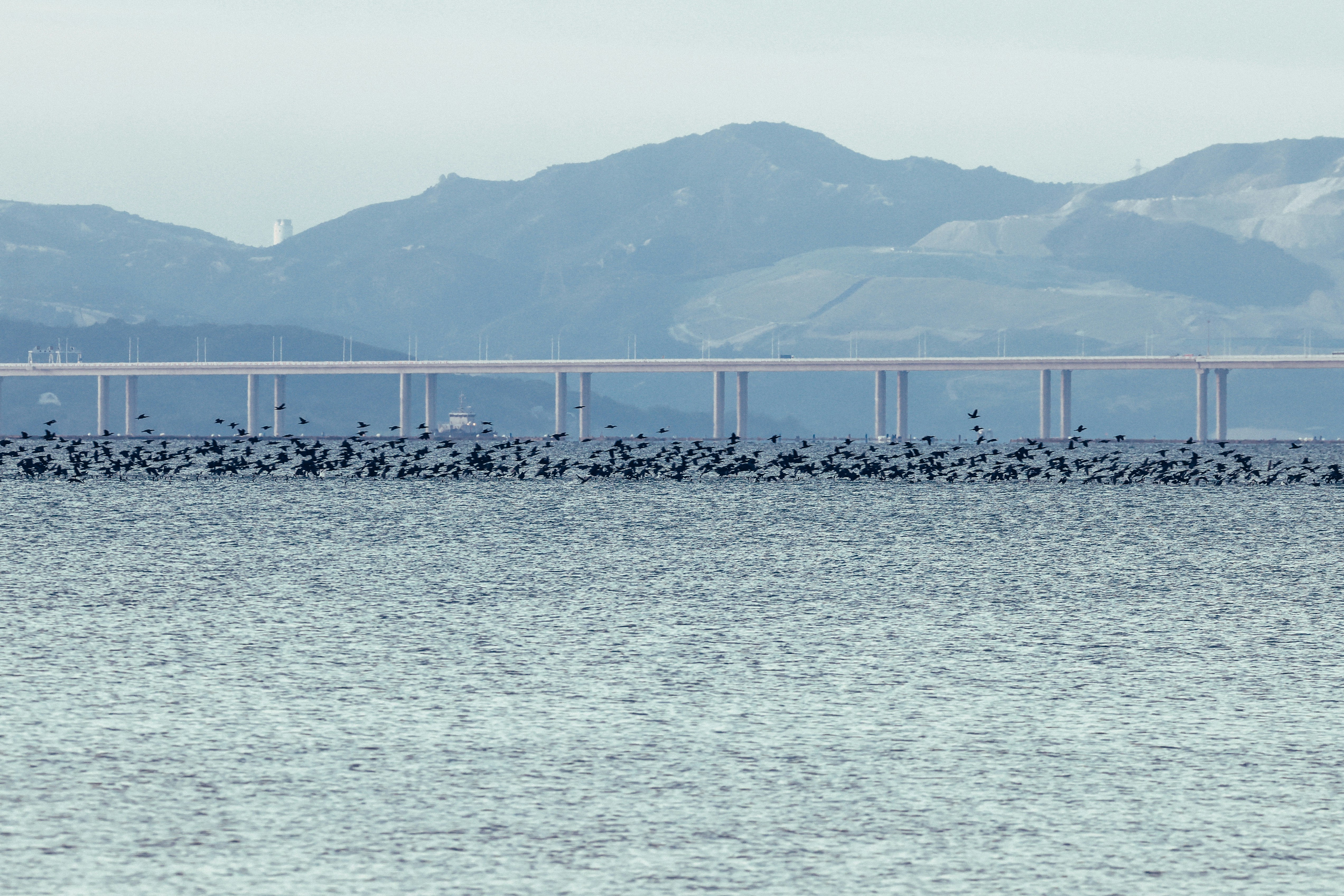 Long bridge over water with distant mountains