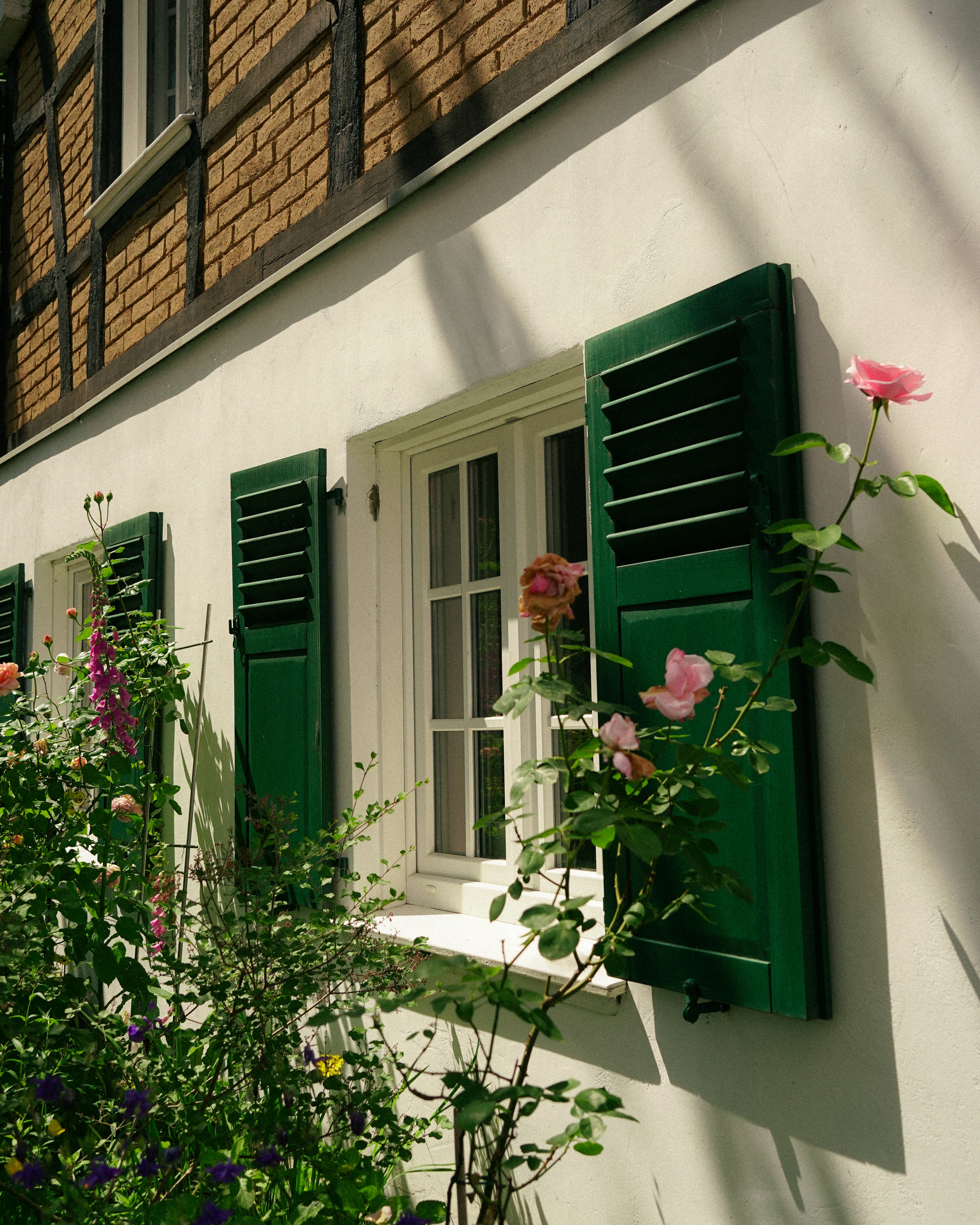 a white house with green shutters and flowers
