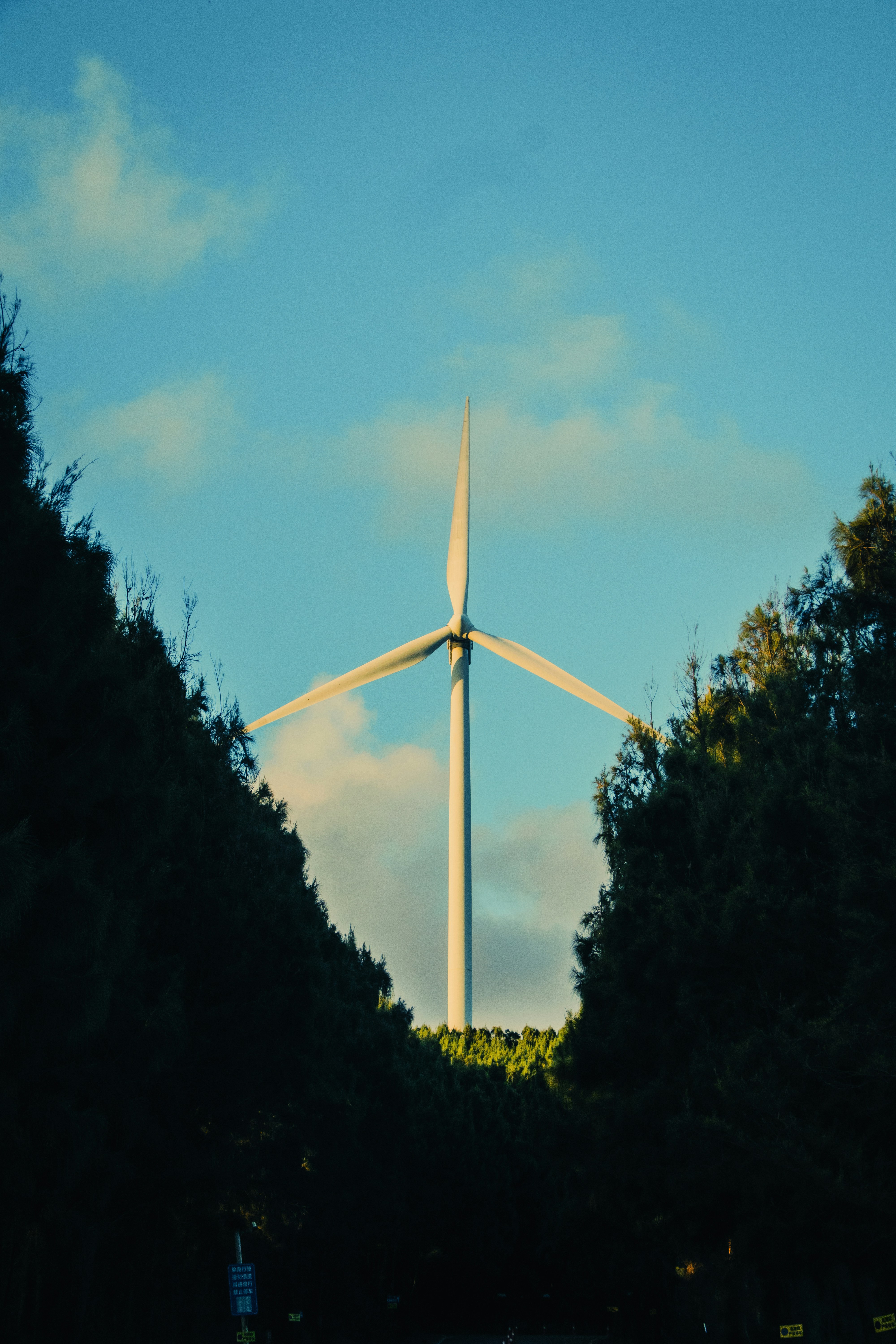 A lone wind turbine stands tall against blue sky.