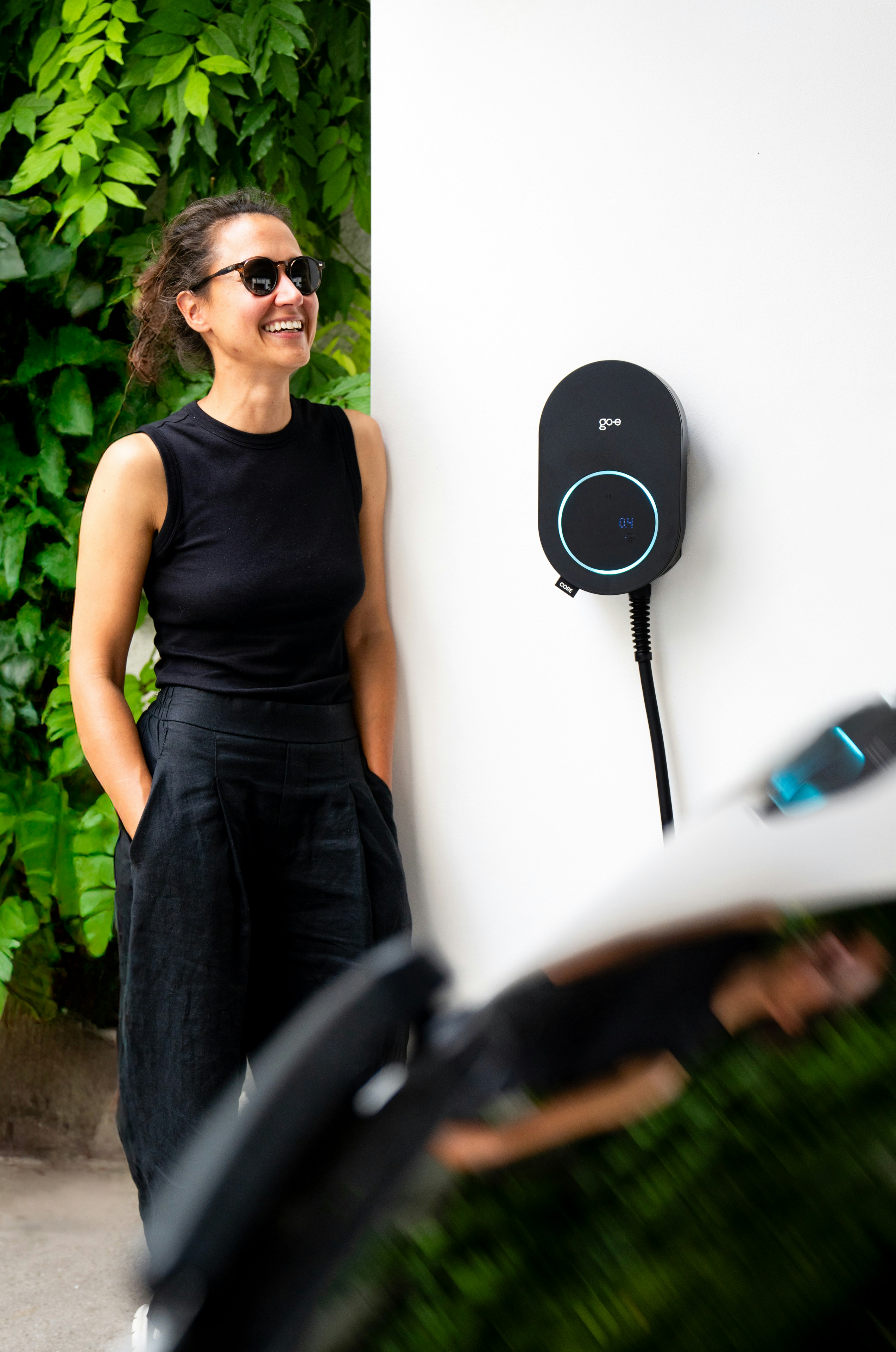 Woman smiling next to an electric car charger.