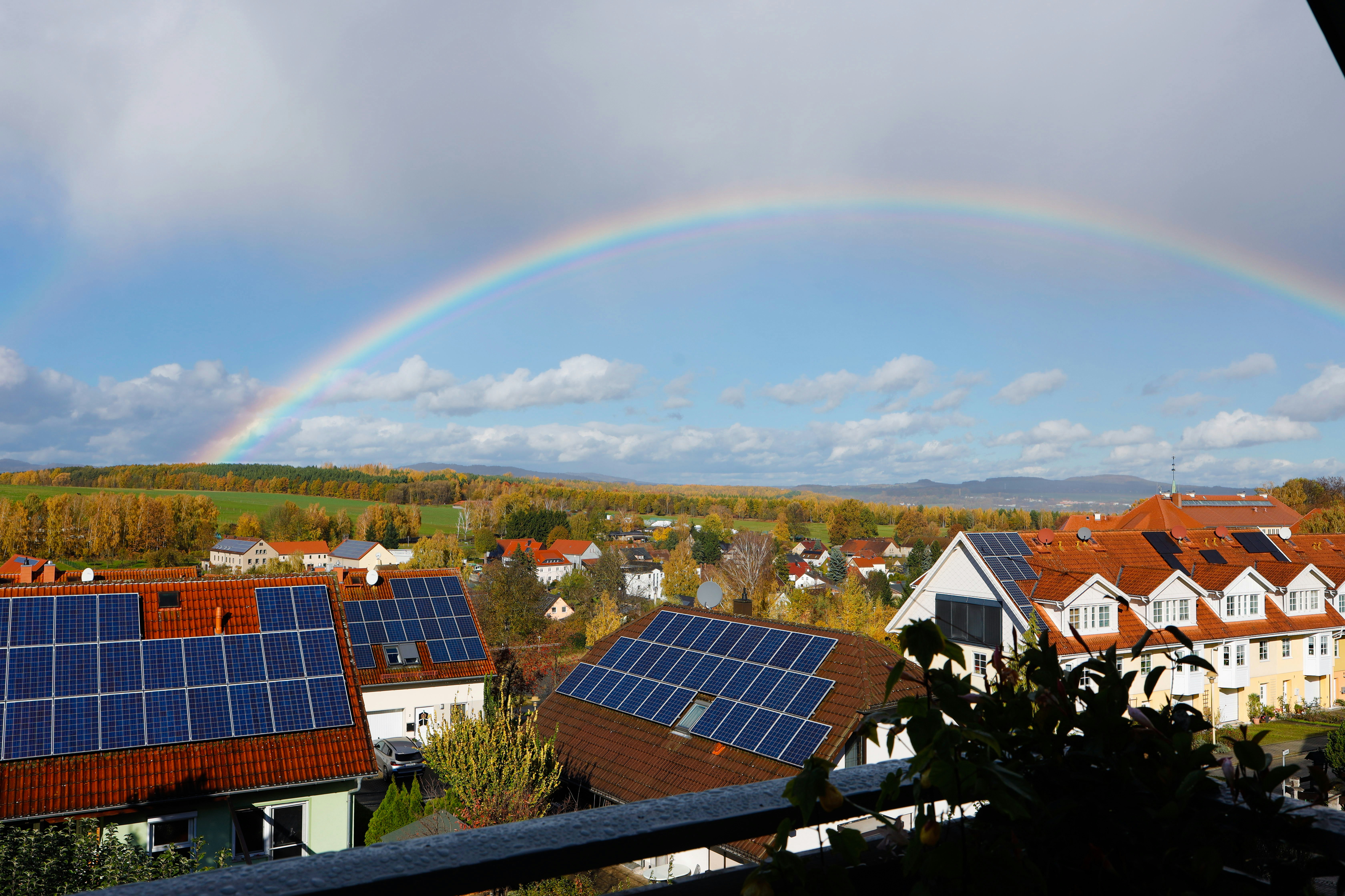 Rainbow over a suburban neighborhood with solar panels.
