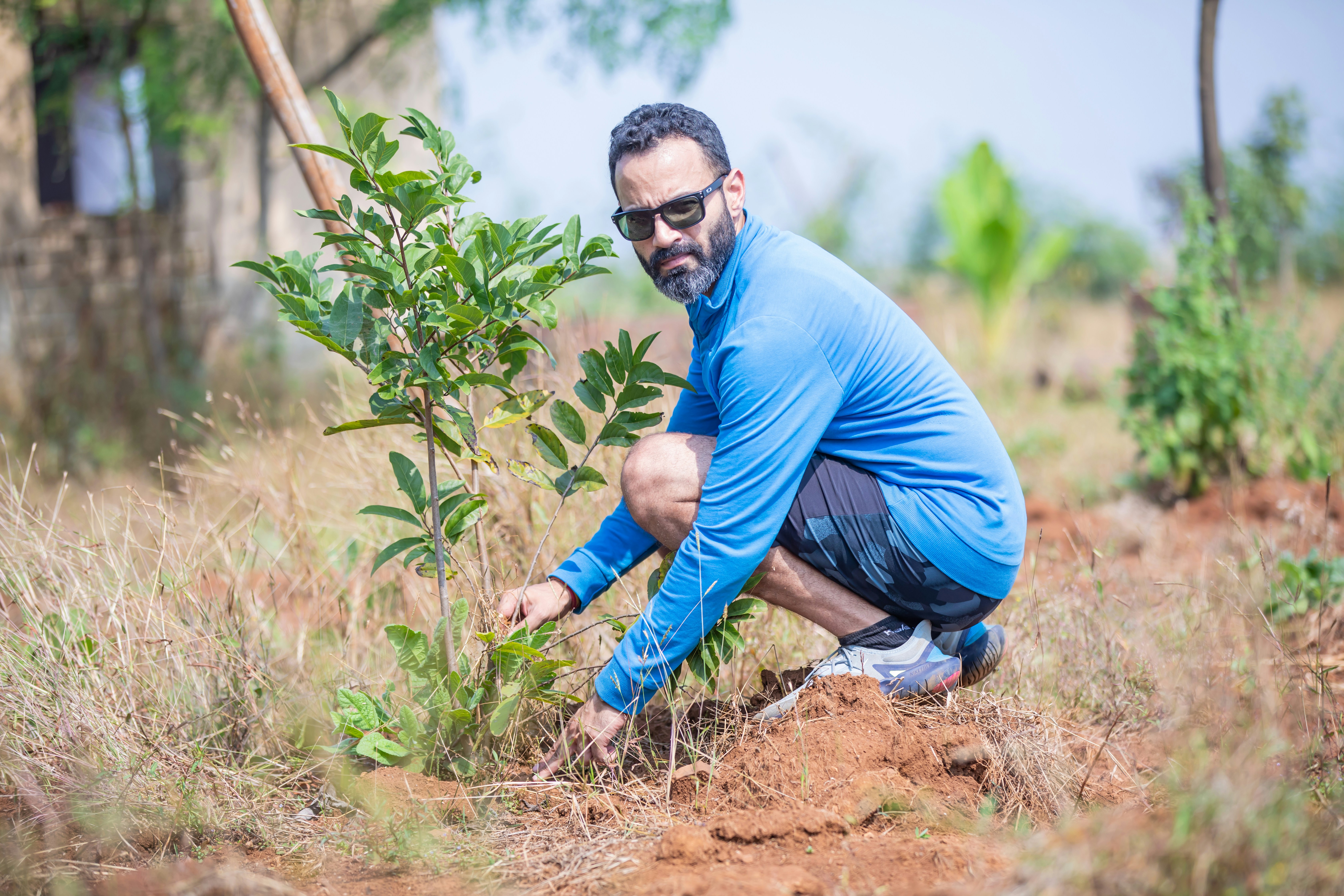 a man kneeling down next to a small tree