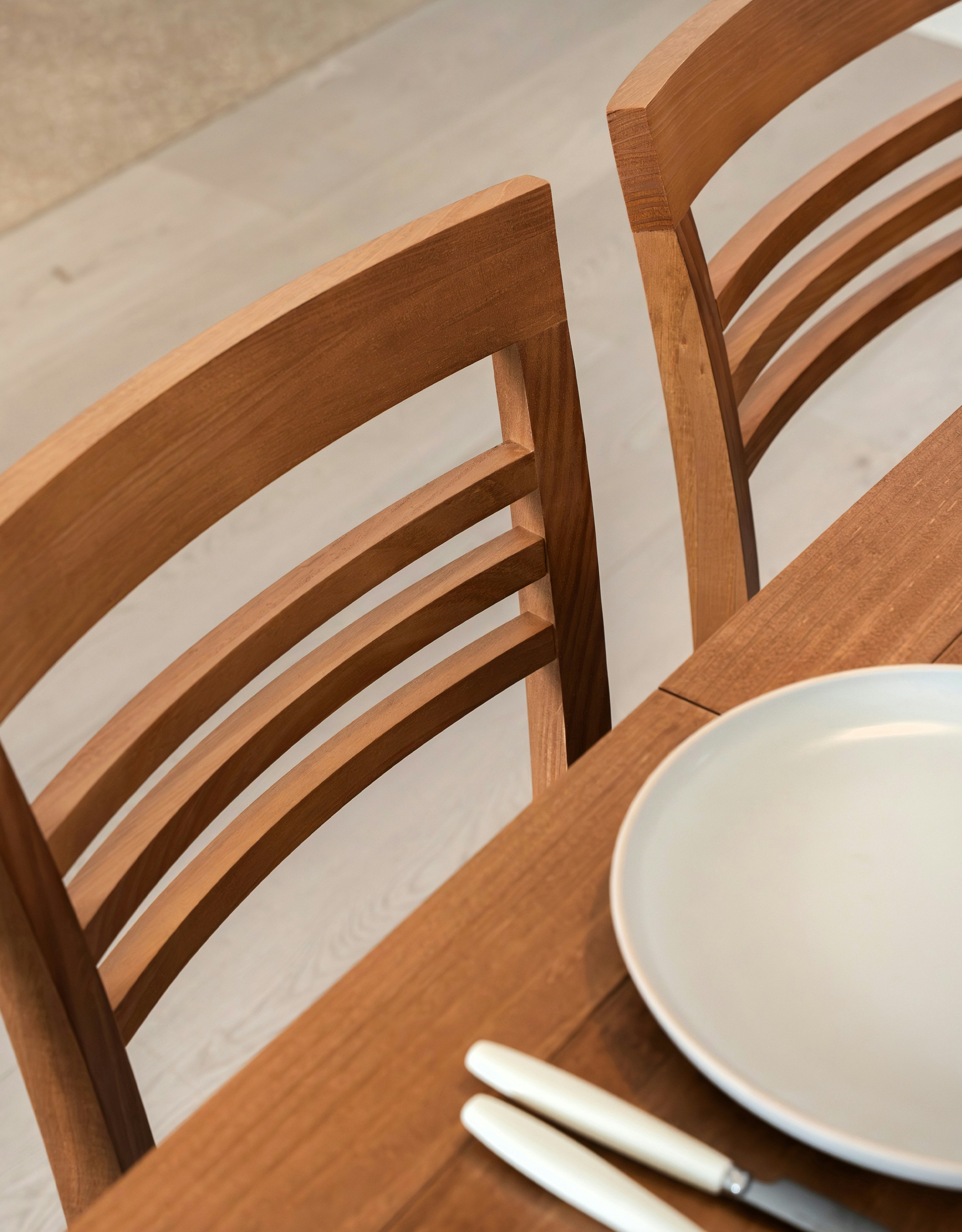 Two wooden chairs at a dining table with plate.