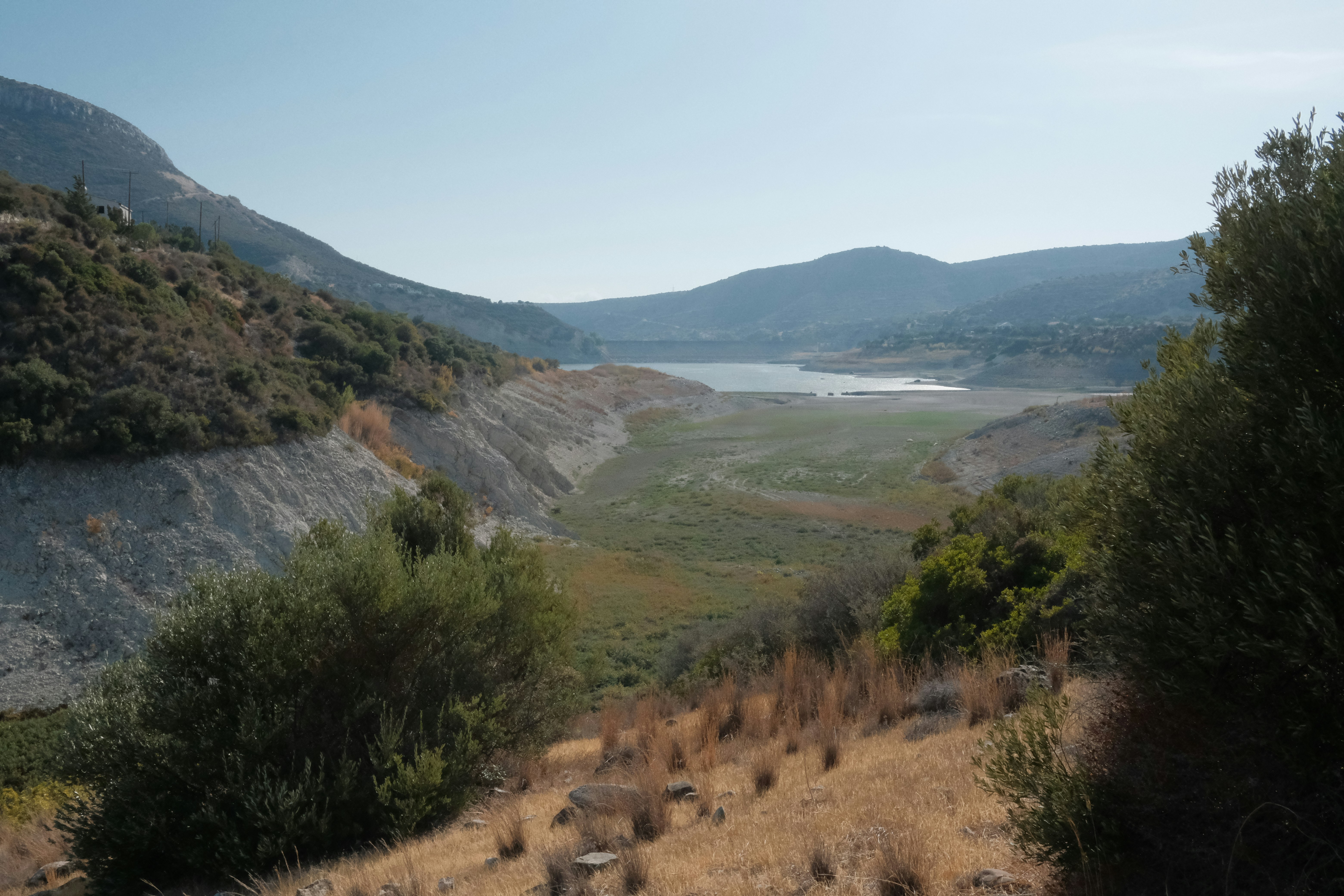 Dry landscape with a distant lake under a clear sky
