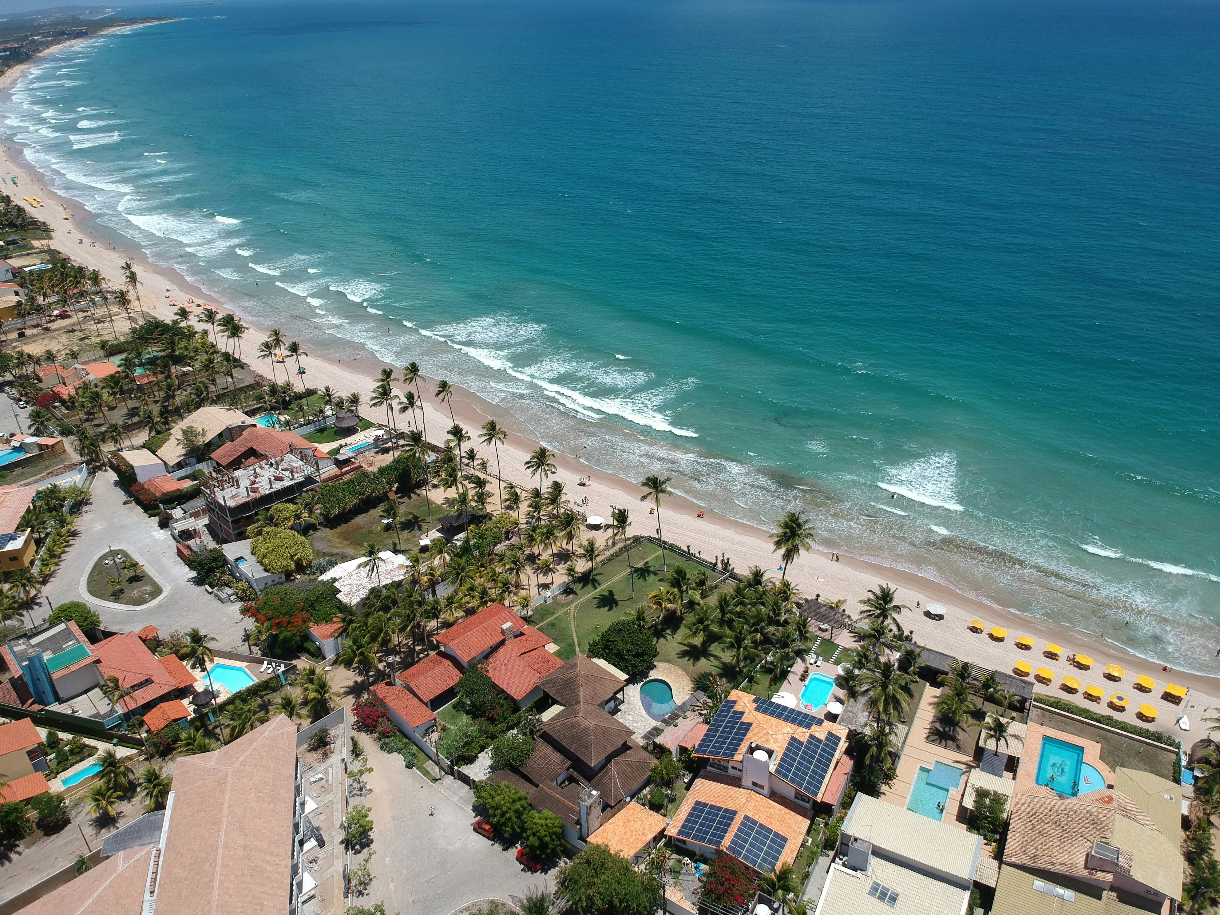 Aerial view of a tropical coastline with resorts and ocean.