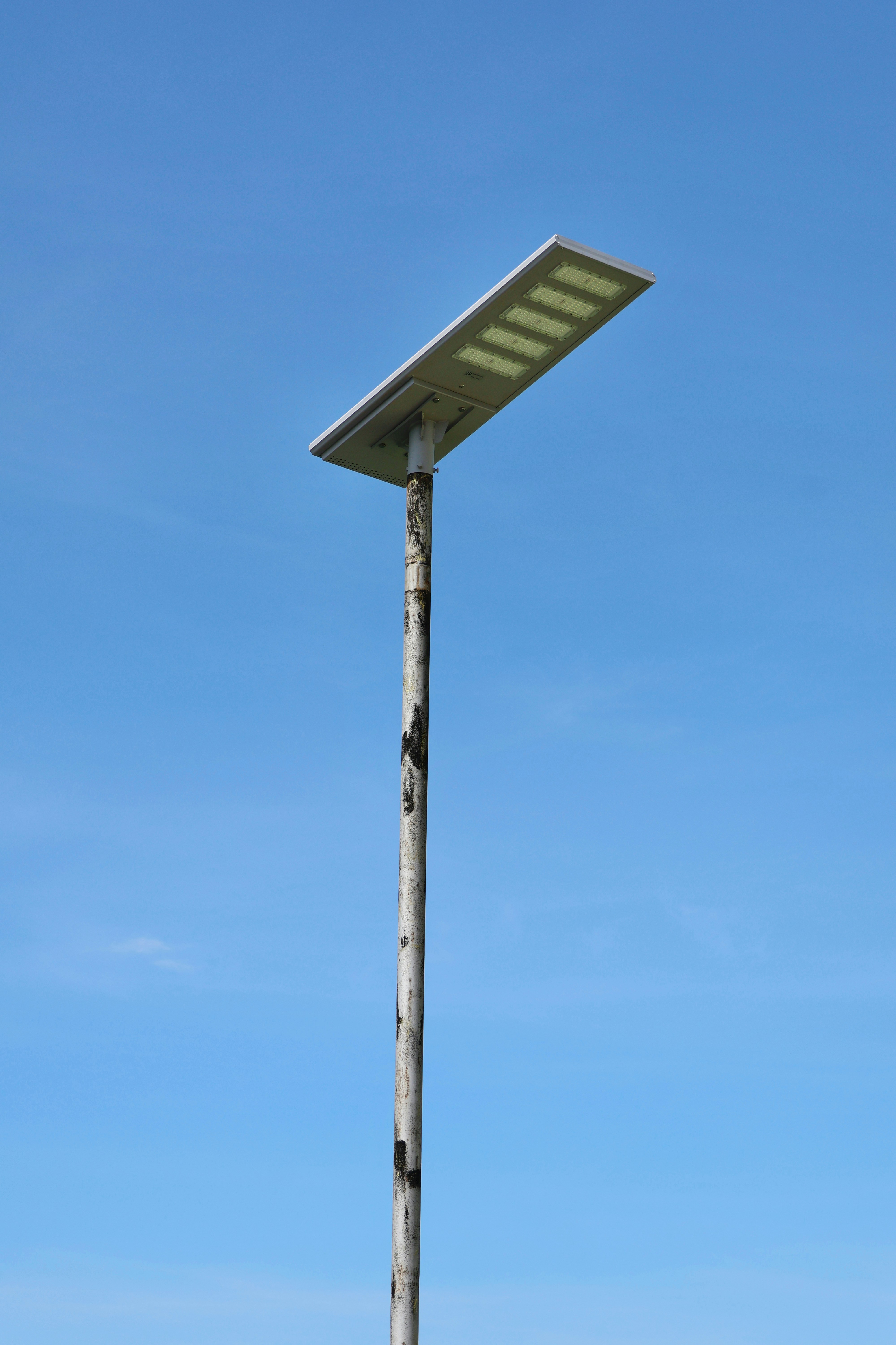 A modern solar-powered street lamp against a clear blue sky.
