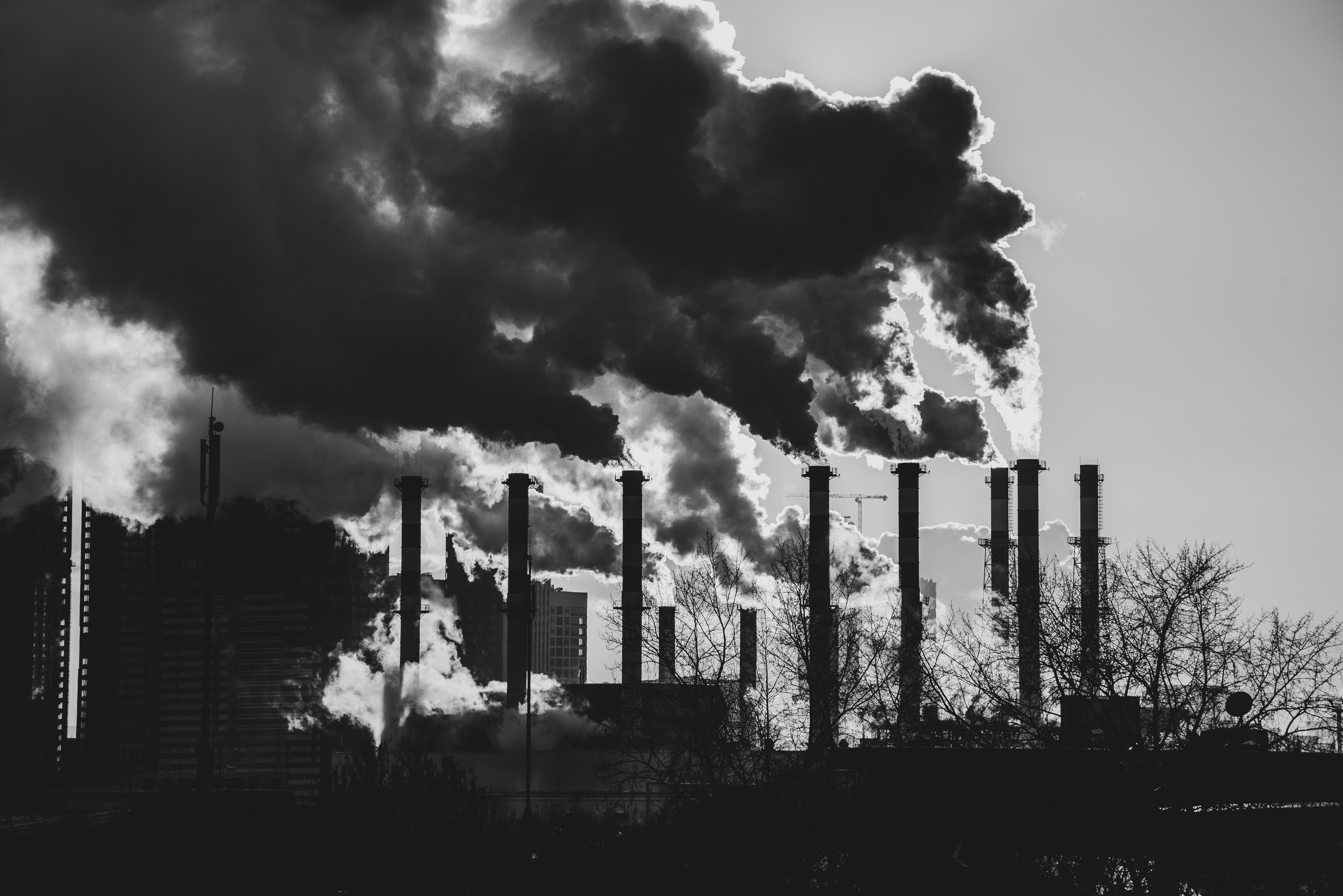 a black and white photo of smoke coming out of a factory
