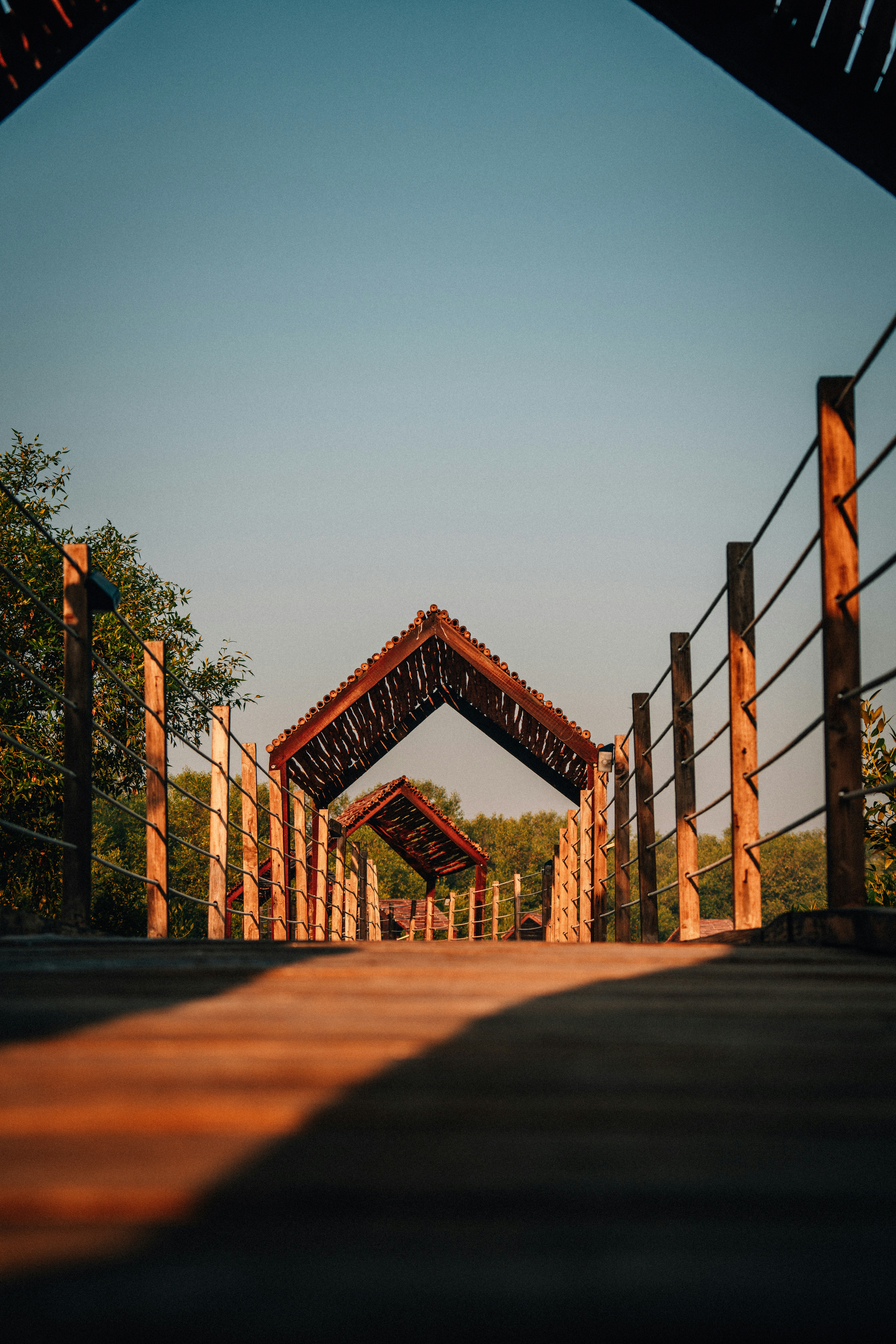 Wooden walkway with covered shelters under clear sky