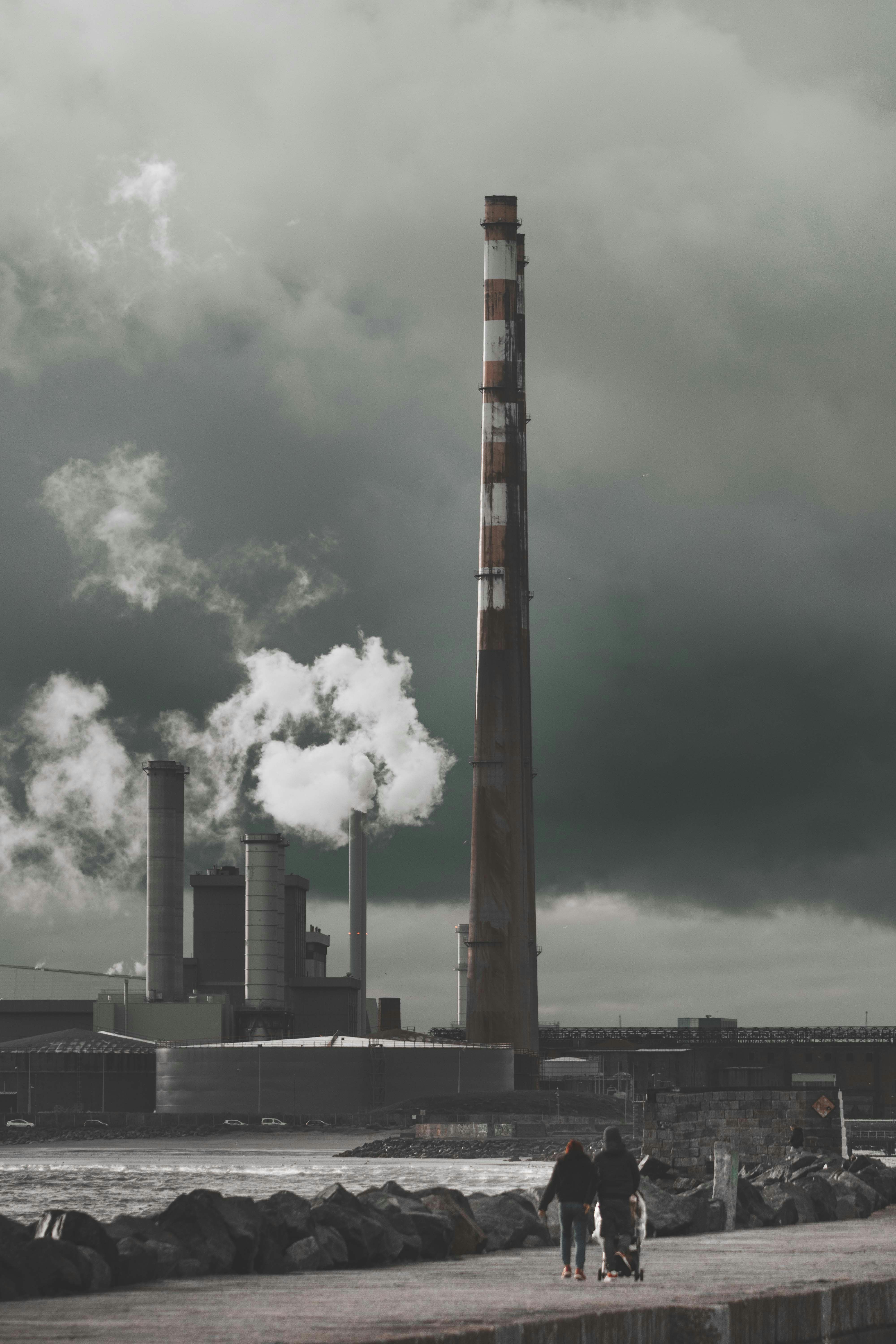 a couple of people walking down a sidewalk next to a factory