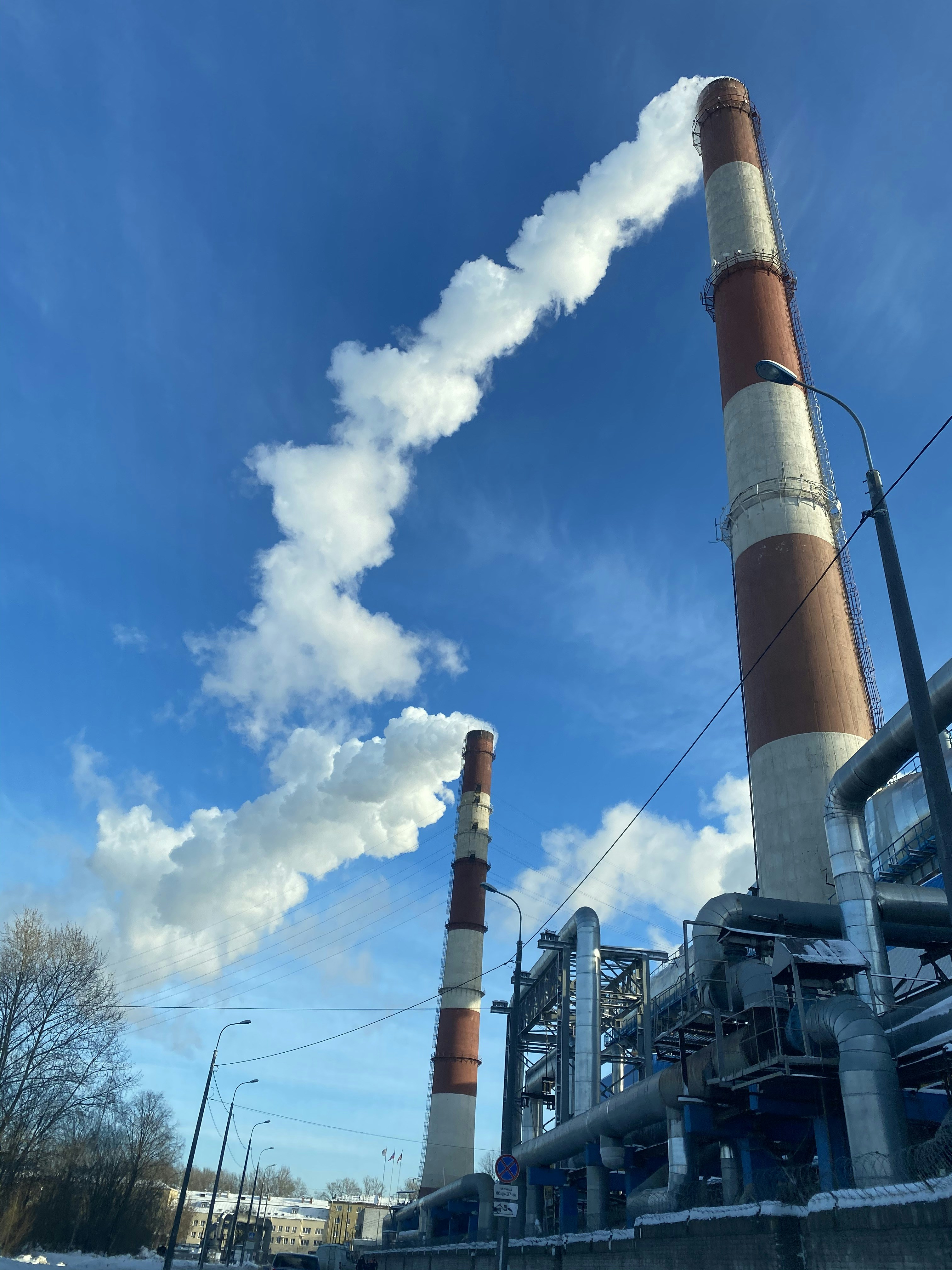 An industrial factory releasing smoke into the air from its tall stacks during operations. by Gone Greenish a factory with smoke coming out of it's stacks