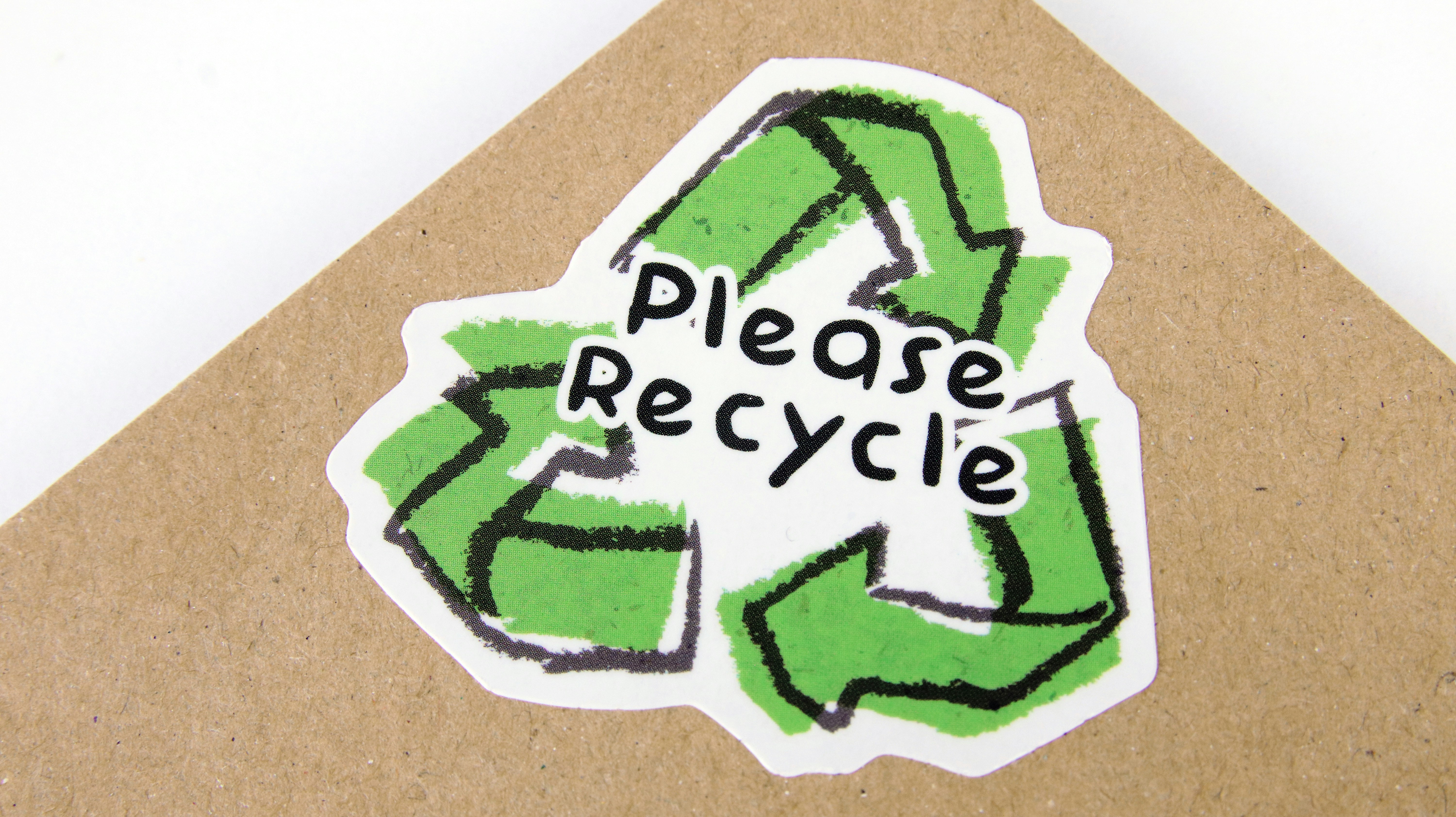 Die cut biodegradable paper sticker with please recycle logo applied to kraft paper envelope by Gone Greenish a green and white pillow