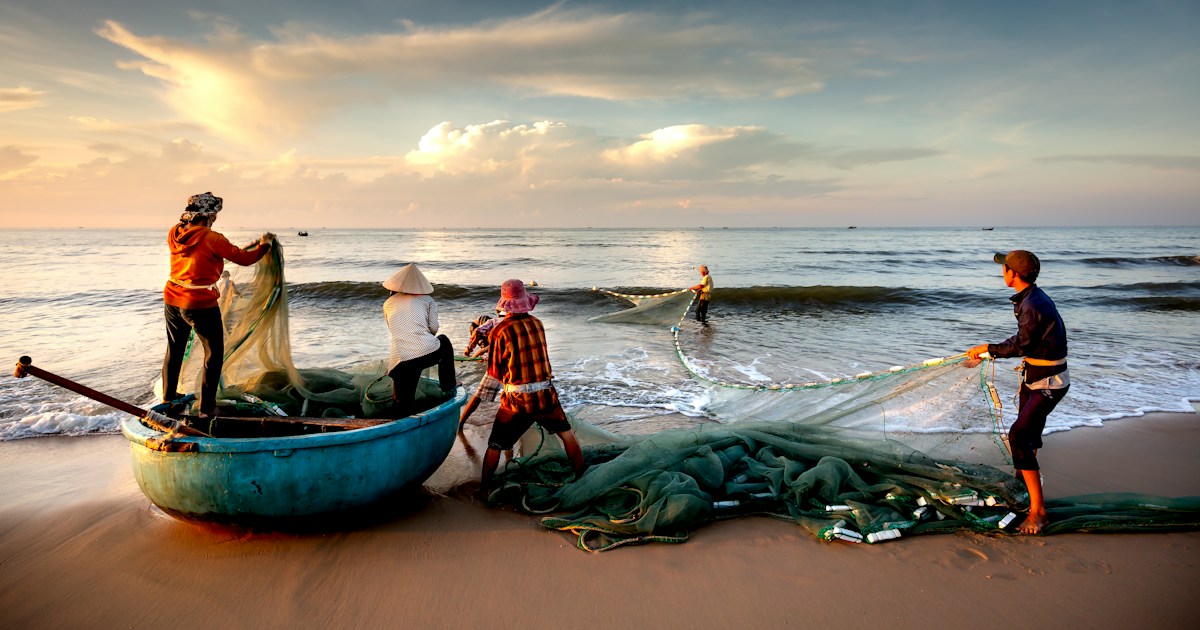 a group of people standing on top of a beach next to a boat