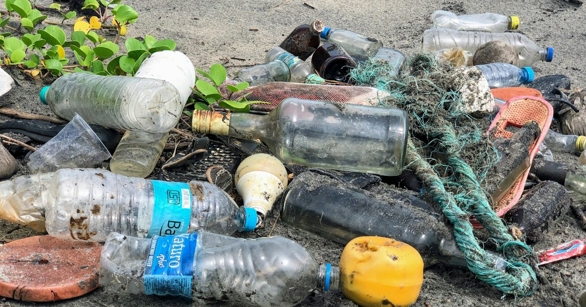 assorted garbage bottles on sandy surface