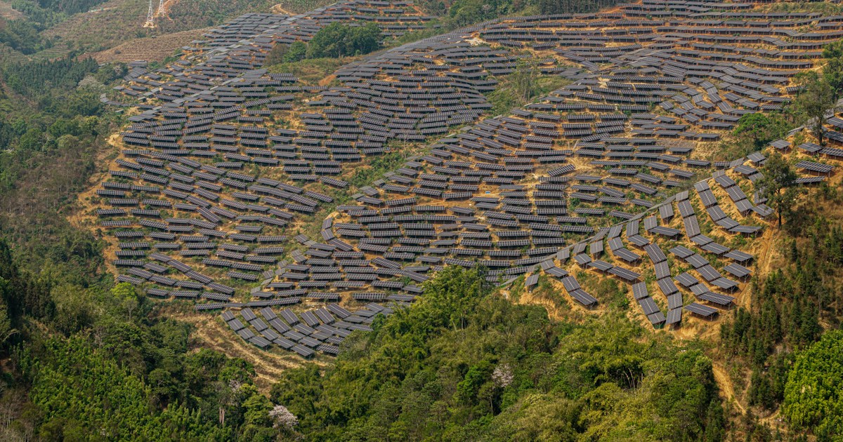 Solar panels cover a hillside in a rural landscape